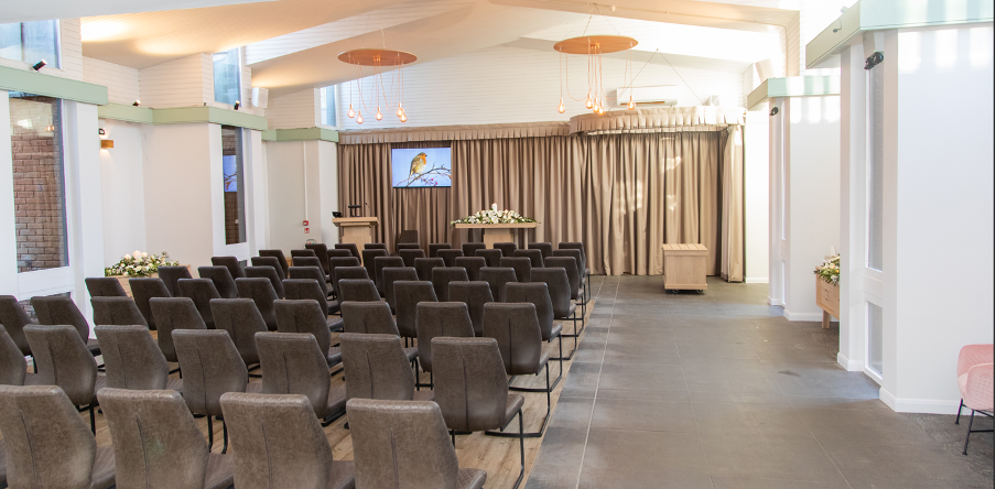 The Cedar Service Room at Bretby Crematorium, arranged with rows of chairs facing the lectern and floral display.